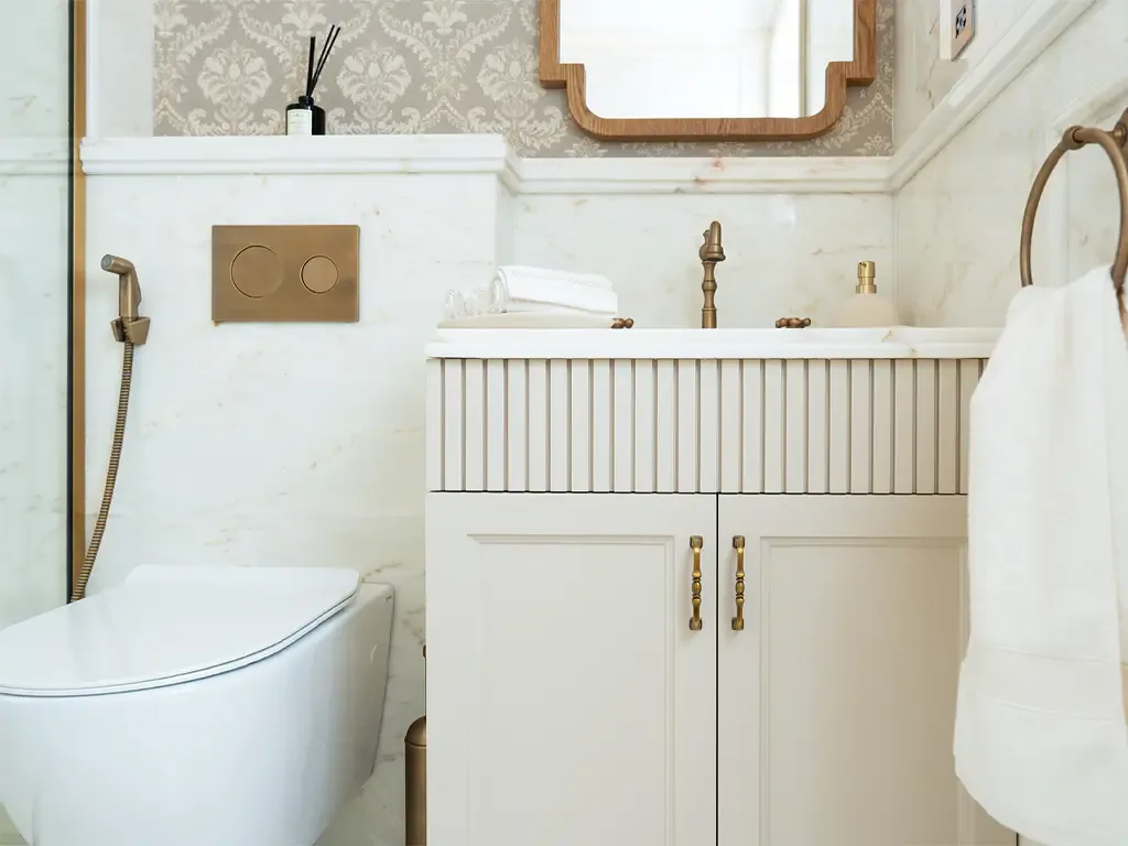 Bathroom with brass fittings, panelled vanity and marble surround in a Bab Al Qasr residence
