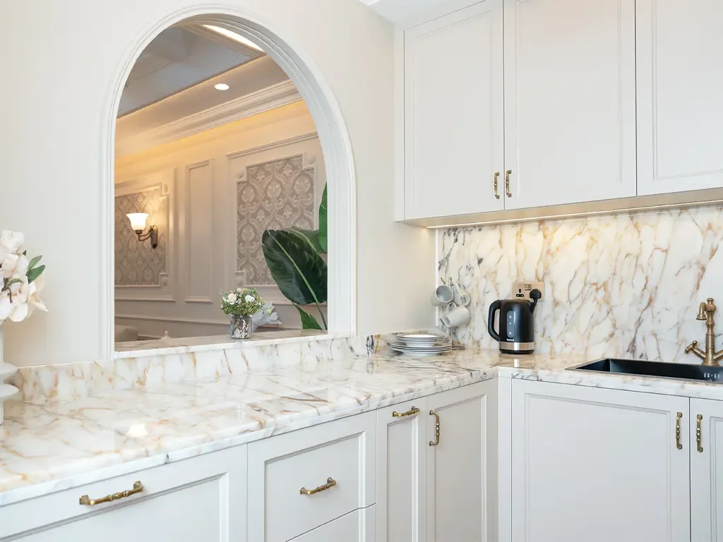 Kitchen in a Bab Al Qasr residence with arched pass-through, marble backsplash and brass hardware