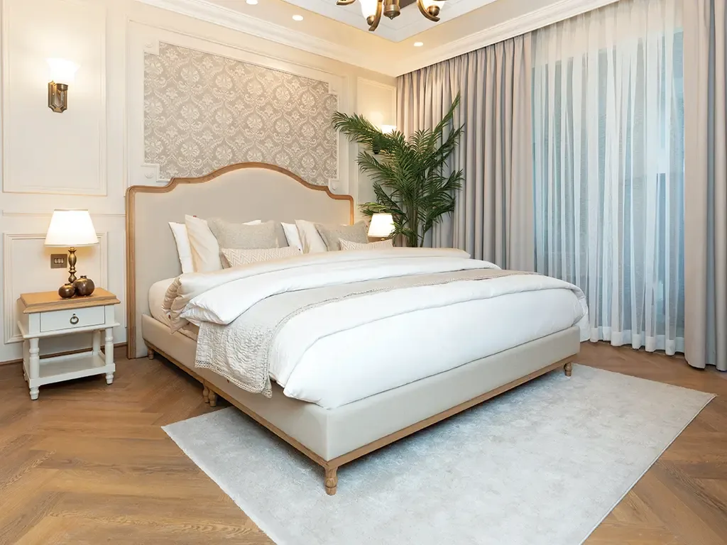 Master bedroom in a Bab Al Qasr residence with upholstered headboard, parquet floor and full-height drapes